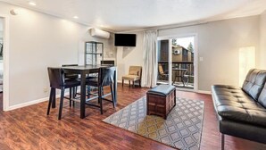 Una sala moderna con comedor, un sofá de cuero y un televisor en la pared.