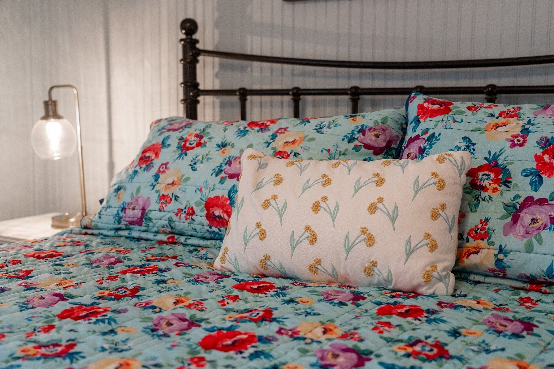 Ein Bett mit blumigem Bettzeug und einem einzelnen Zierkissen.