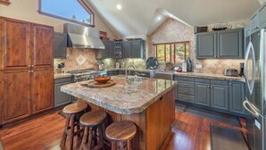 Una cocina con una isla grande, taburetes de madera y un salpicadero de piedra.