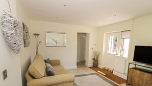 A living room with a sofa, a television, and a framed picture on the wall. - Garden Cottage (Worcester)