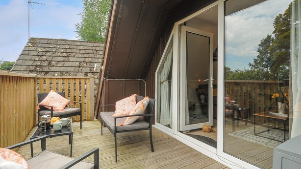 Una terrazza con mobili da esterno, una porta scorrevole in vetro che dà su un patio e un recinto in legno.