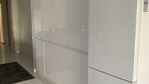 Une cuisine moderne avec des meubles blancs, un réfrigérateur et un sol carrelé.