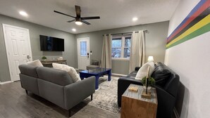 A living room with a gray sofa, a black sofa, a wooden coffee table, and a ceiling fan.