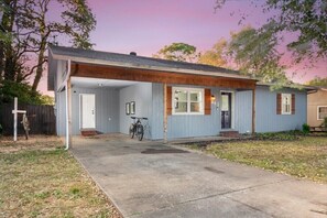 A single-story house with a covered porch, a bicycle parked outside, and a number '203' on the door.
