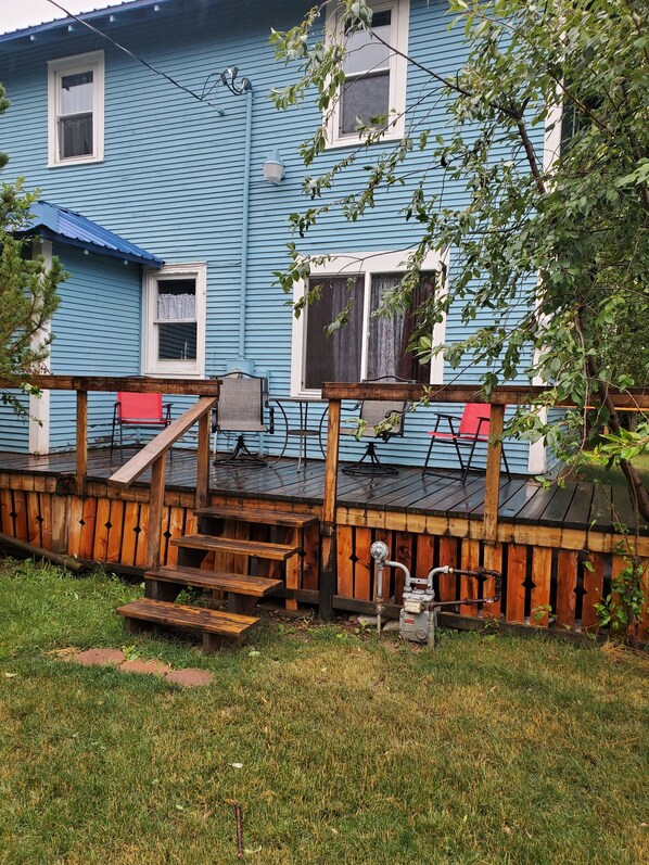 A blue house with a wooden deck, a red chair, and a small table. - Rustic Farmhouse-Walk to Main Street Augusta  (Augusta,)