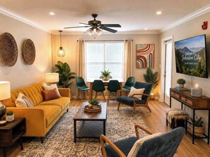 A living room with a sofa, chairs, a coffee table, a TV, and a ceiling fan.