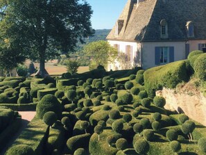 A landscaped garden with neatly trimmed hedges and a building with a steep roof. - LE CLOS SAINT MARTIAL (Saint-Martial-de-Nabirat)