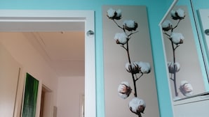 A room with a teal wall, a door, and a framed cotton plant artwork.