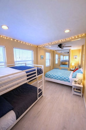 A bedroom with two bunk beds, a ceiling fan, a mirror, and a bedside table with a lamp.