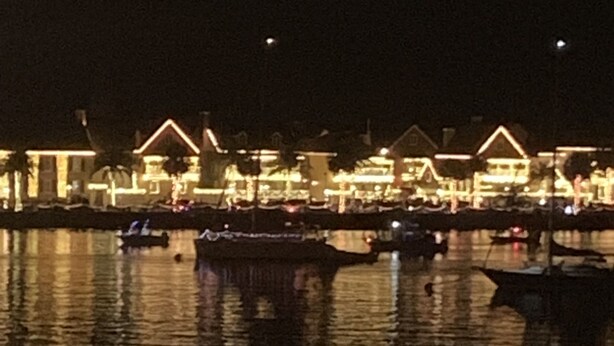 Un hôtel situé au bord de l’eau, avec de nombreux bateaux amarrés, des bâtiments illuminés et une surface d’eau calme qui reflète les lumières.