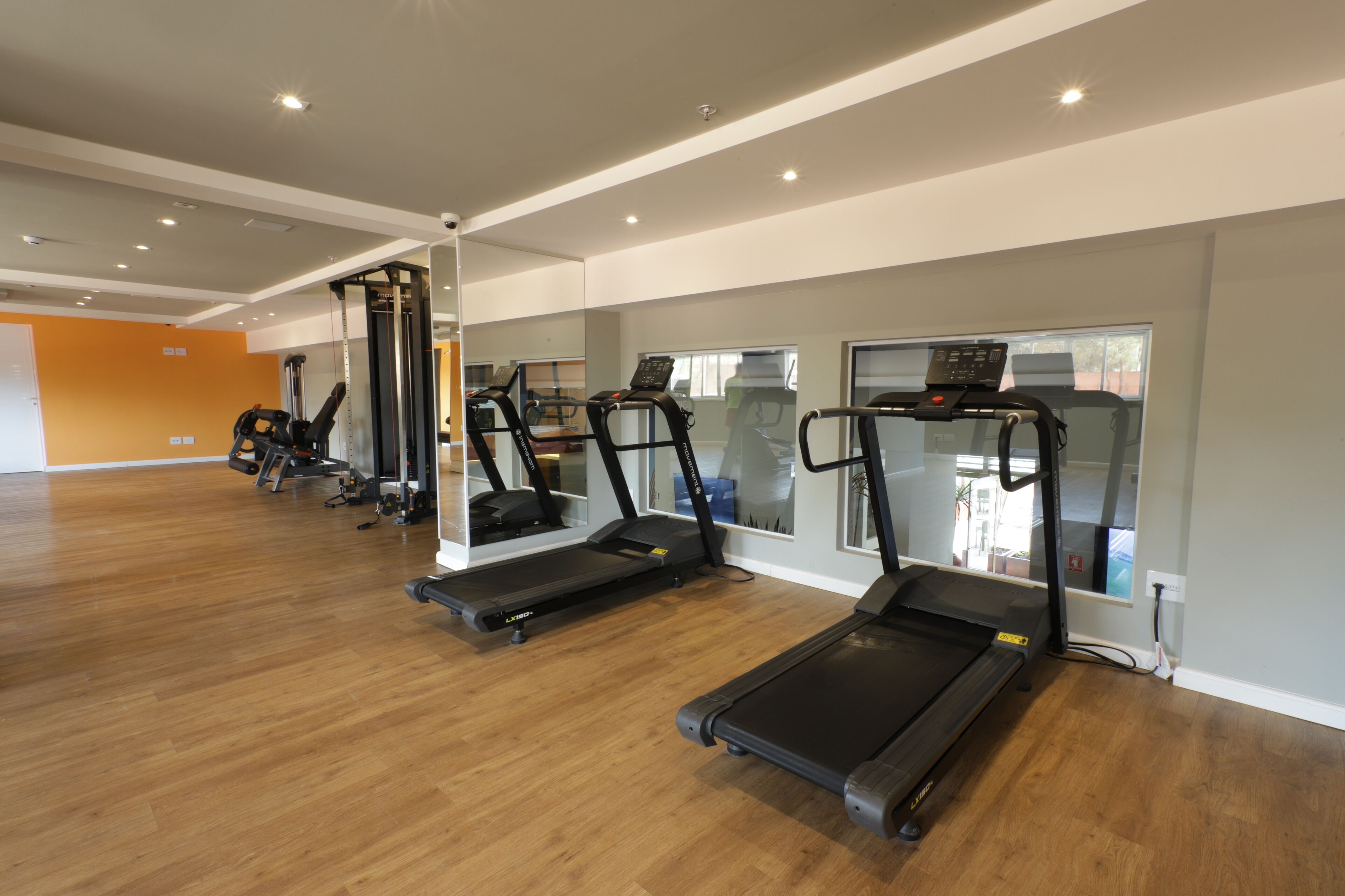 A gym with treadmills, a weight machine, and a mirror wall.