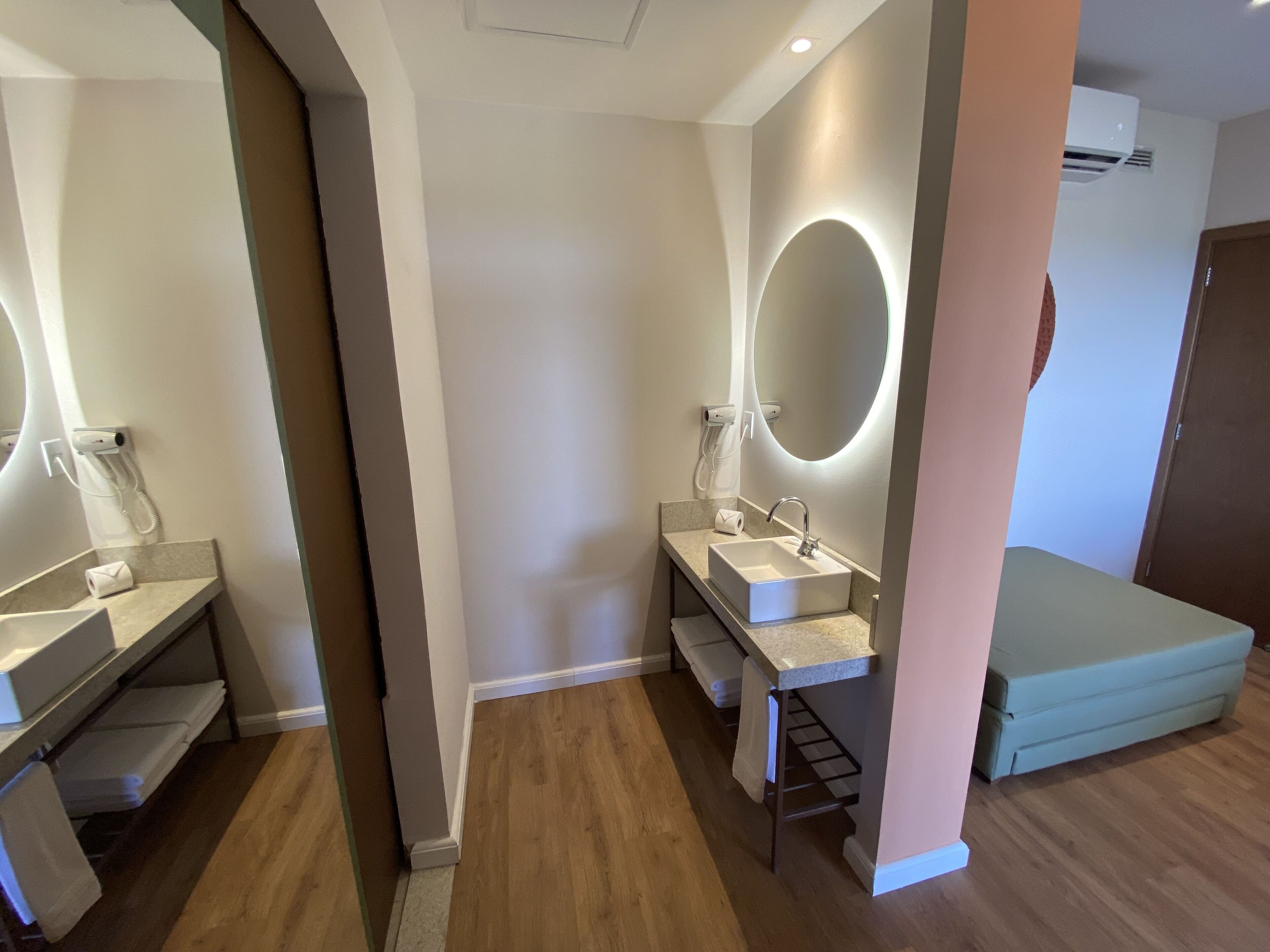 Un baño moderno con dos lavamanos, un espejo grande y un banco empotrado.