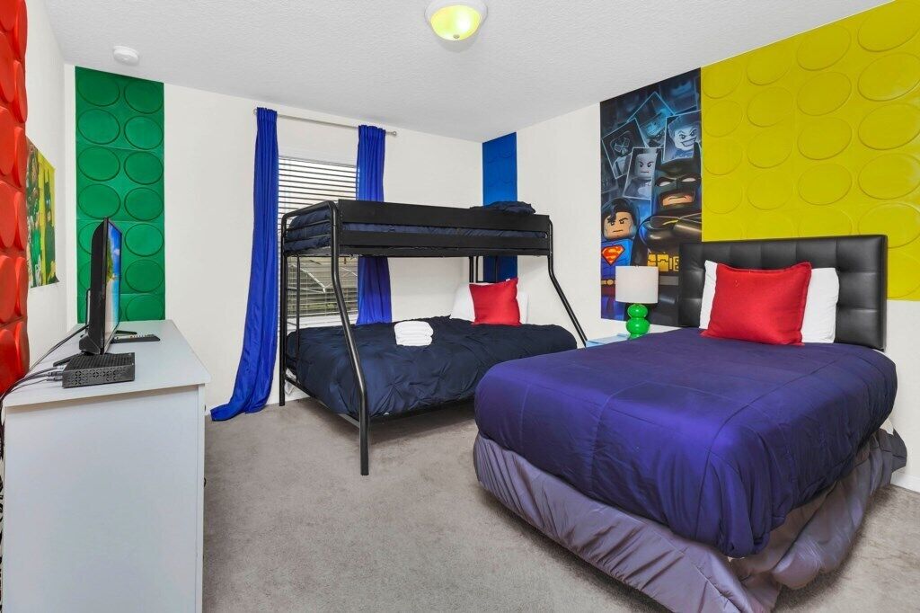 Ein Zimmer mit Etagenbetten, einem Schreibtisch mit Computer und Wandgestaltung im Superhelden-Look.