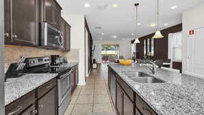 Una cocina moderna con armarios oscuros, encimeras de granito y electrodomésticos de acero inoxidable.
