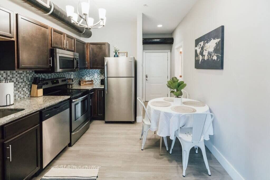 A modern kitchen with dark wooden cabinets, stainless steel appliances, and a tiled backsplash.