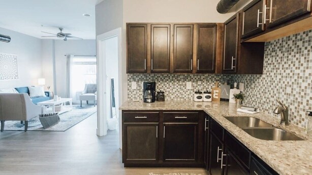 Una cocina moderna con armarios de madera oscura, salpicadero de azulejos y electrodomésticos de acero inoxidable.