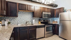 Una cocina moderna con armarios de madera oscura, salpicadero de azulejos, electrodomésticos de acero inoxidable y encimera de granito.
