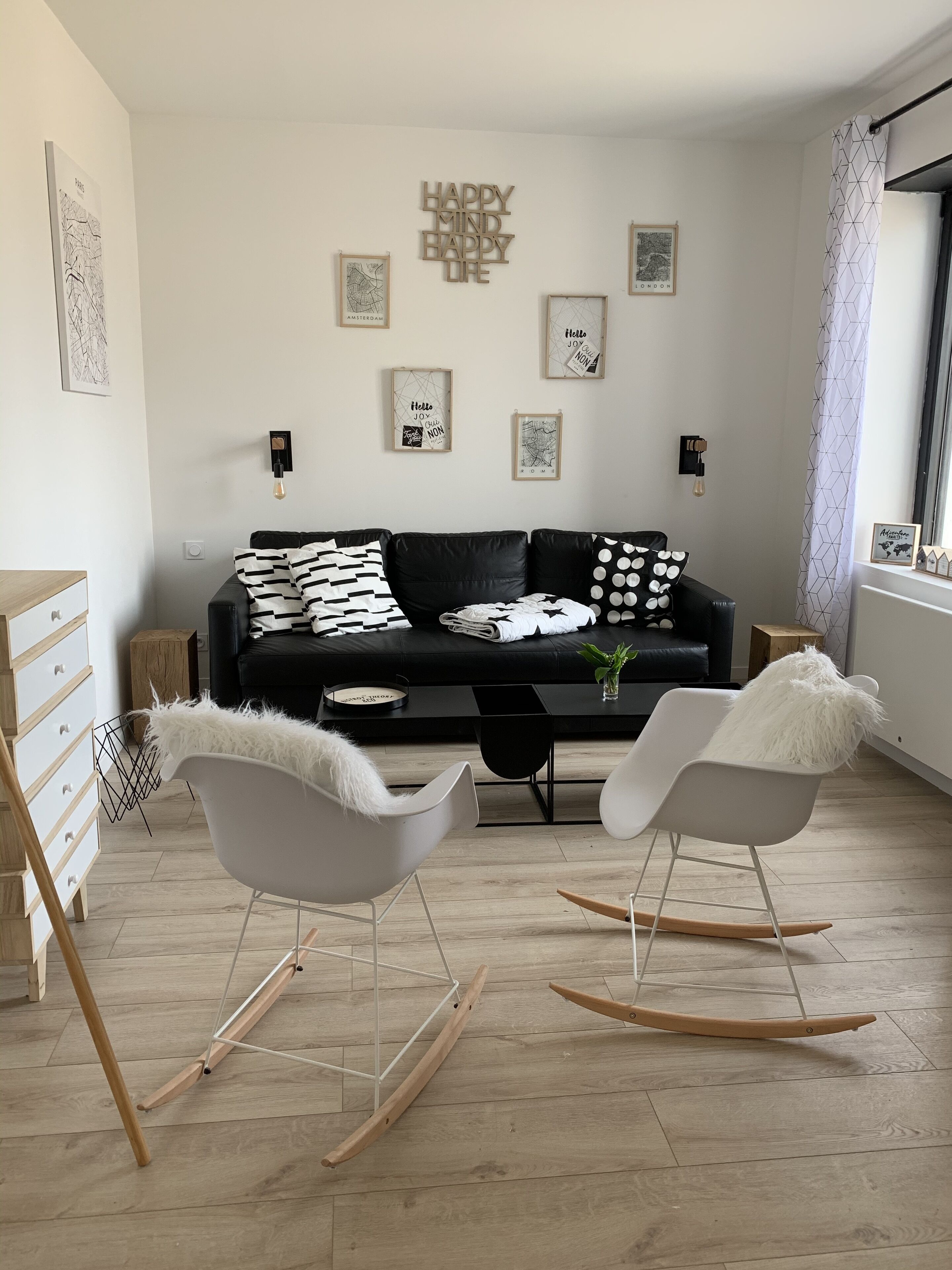 A modern living room with a black sofa, two rocking chairs, and a coffee table.