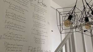 Een trap met een witte leuning en een muur met handgeschreven tekst in het Frans.