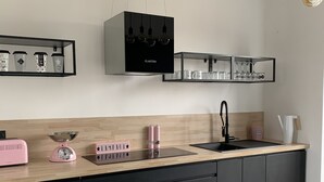 Een moderne keuken met zwarte kastjes, een houten aanrechtblad, een zwarte afzuigkap en hangende lampen.