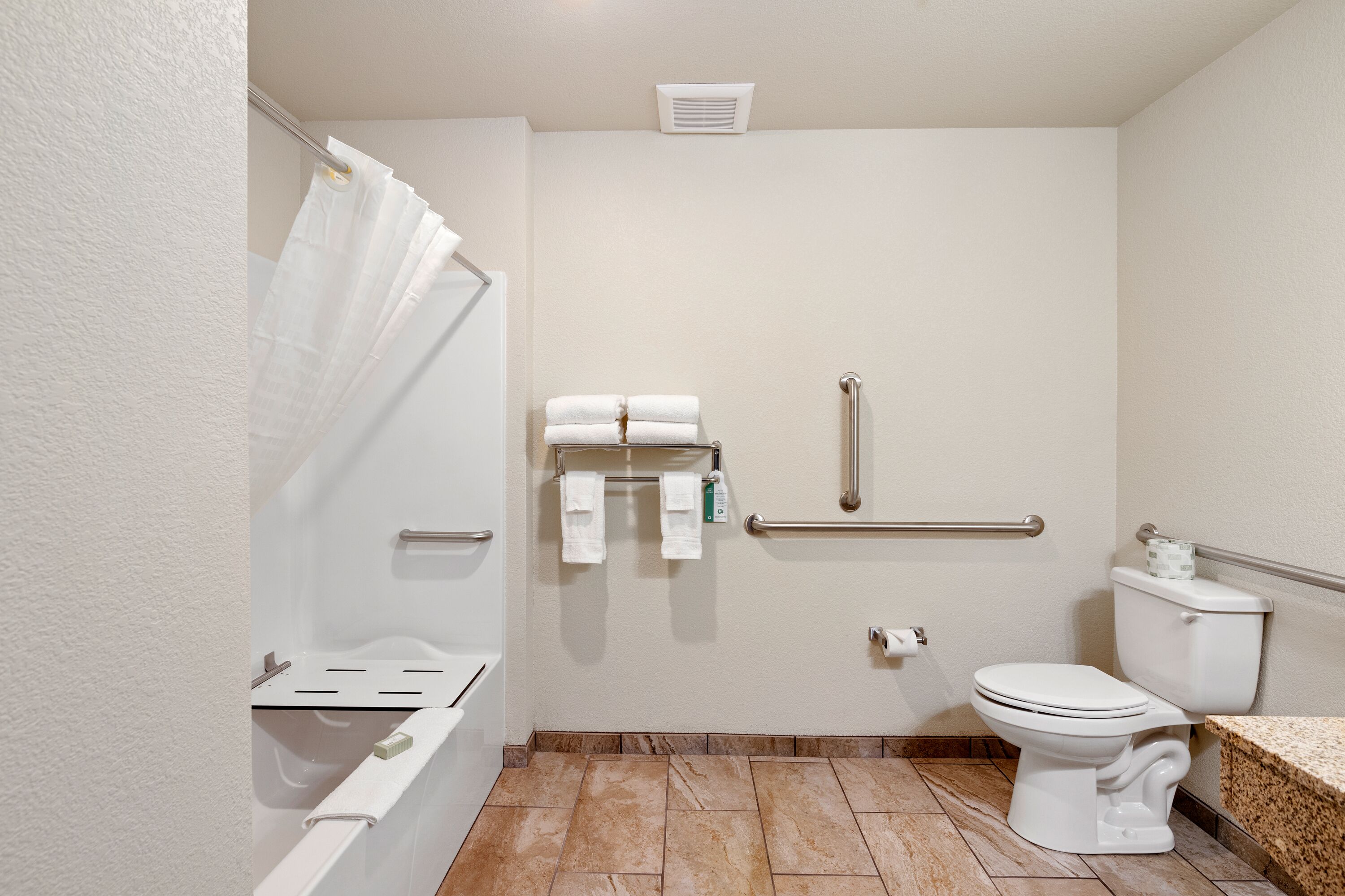 A bathroom with a shower, toilet, and grab bars.