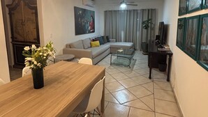 A modern living room with a sofa, coffee table, and dining area with chairs and a wooden table. - LUNA • Calm 2BR 2BA Apartment • Fast WiFi • Spacious Stay (Puerto Vallarta)