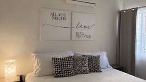 A bedroom with a bed, a ceiling fan, an air conditioning unit, and two motivational wall art pieces. - LUNA • Calm 2BR 2BA Apartment • Fast WiFi • Spacious Stay (Puerto Vallarta)