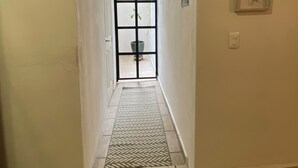 A hallway with a patterned rug, a door leading to a room, and three starfish decorations on the wall. - LUNA • Calm 2BR 2BA Apartment • Fast WiFi • Spacious Stay (Puerto Vallarta)