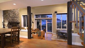 Un amplio espacio de sala con chimenea de piedra, una mesa de comedor y una escalera.
