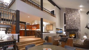 Amplia sala de estar con chimenea, una mesa de comedor y una cocina al fondo.