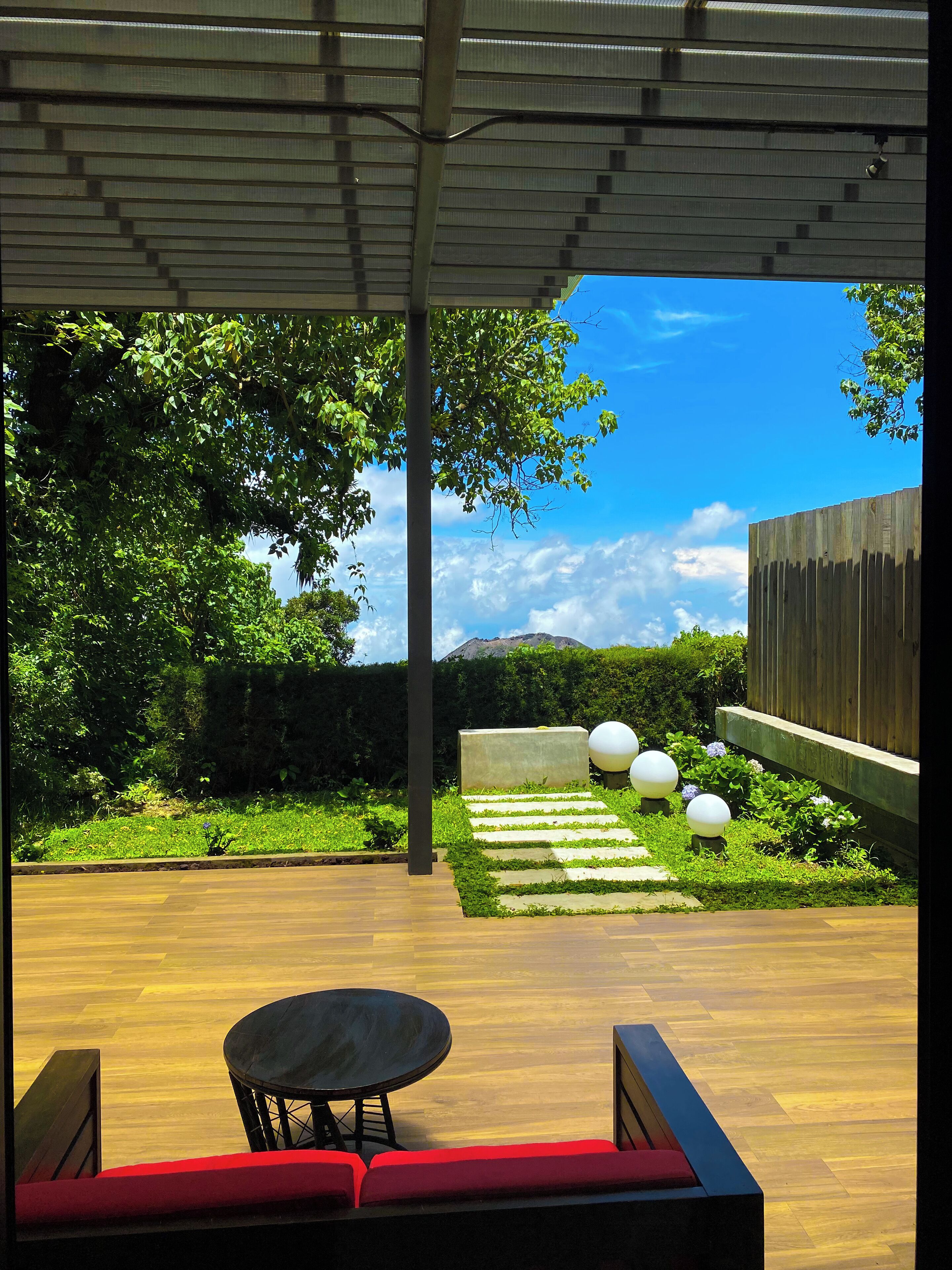 An outdoor patio with a wooden floor, a round table, and red cushioned seating.
