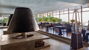 Un espacio exterior moderno con una lámpara de mesa grande, asientos cómodos y ventanas amplias con vistas del entorno.