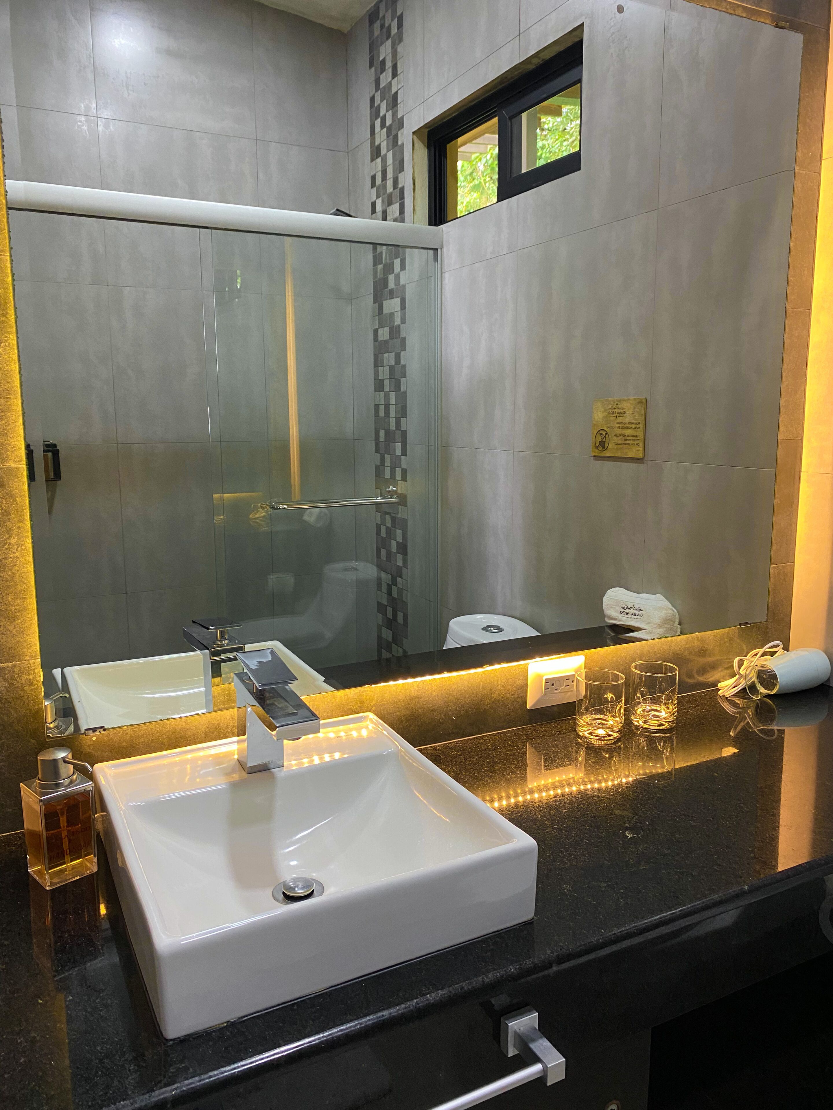 A modern bathroom with a large mirror, a white sink, and a glass shower enclosure.