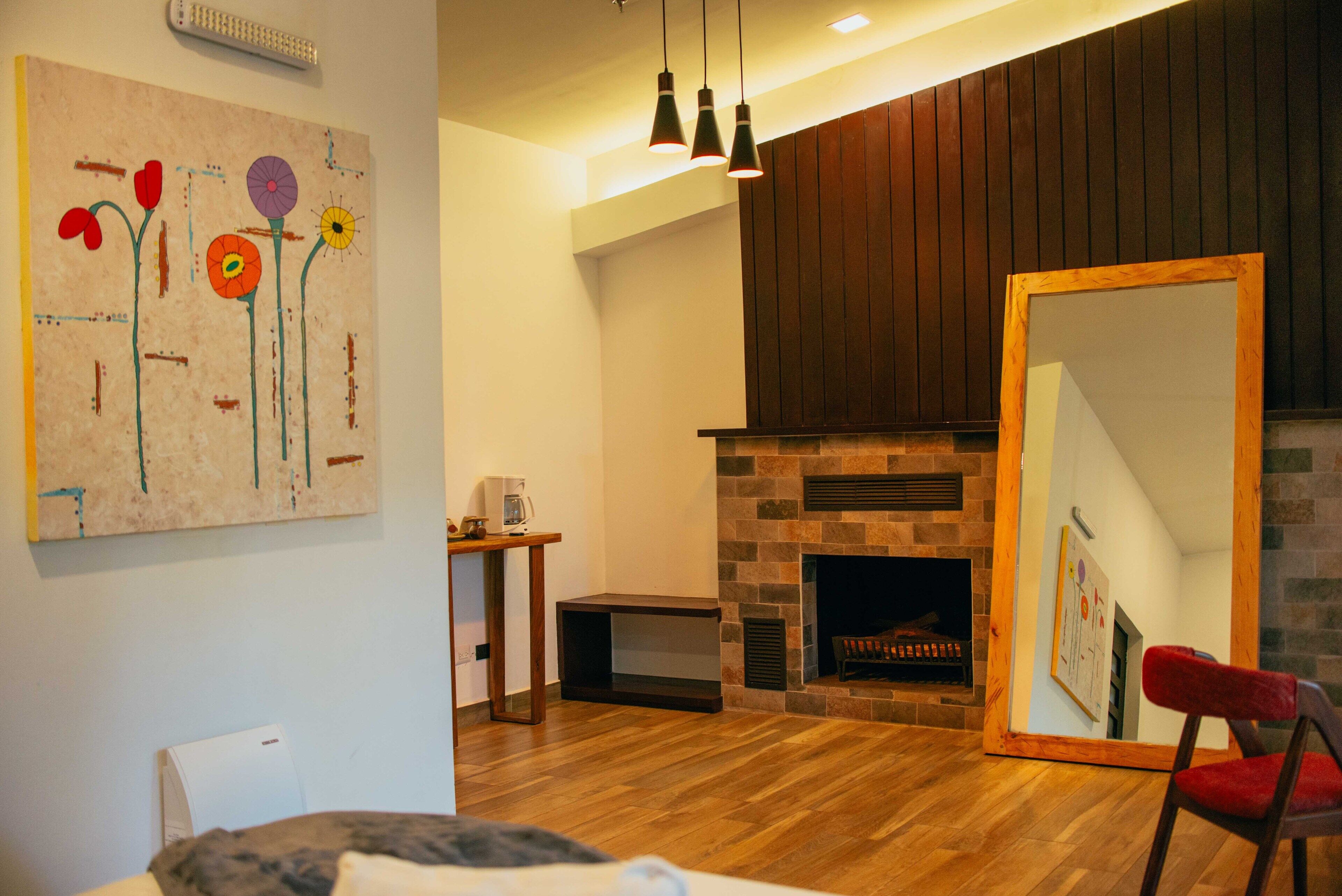 Una sala de estar moderna con chimenea, pisos de madera y un cuadro abstracto grande en la pared.