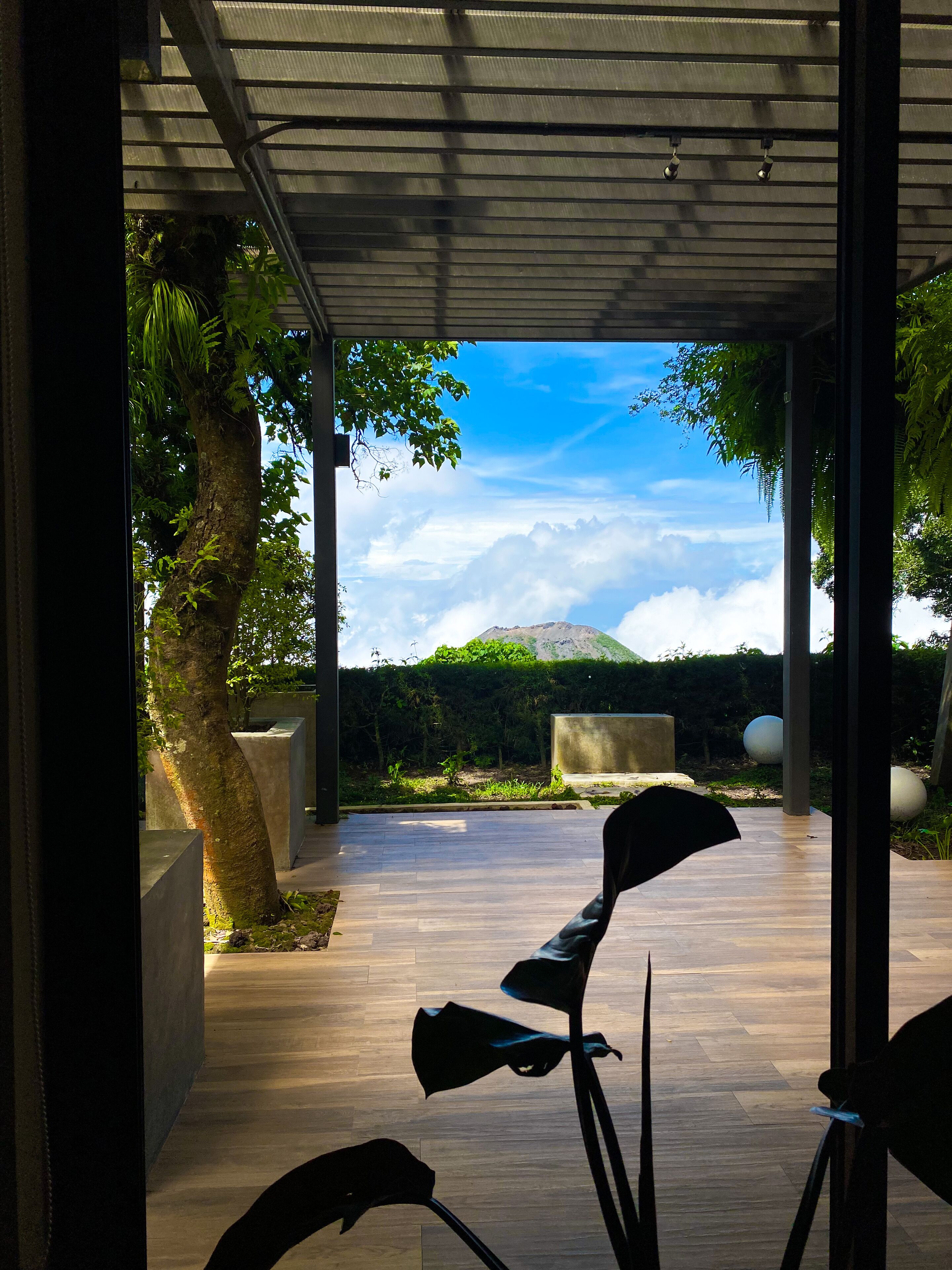 A covered outdoor area with a view of a mountain and clouds.