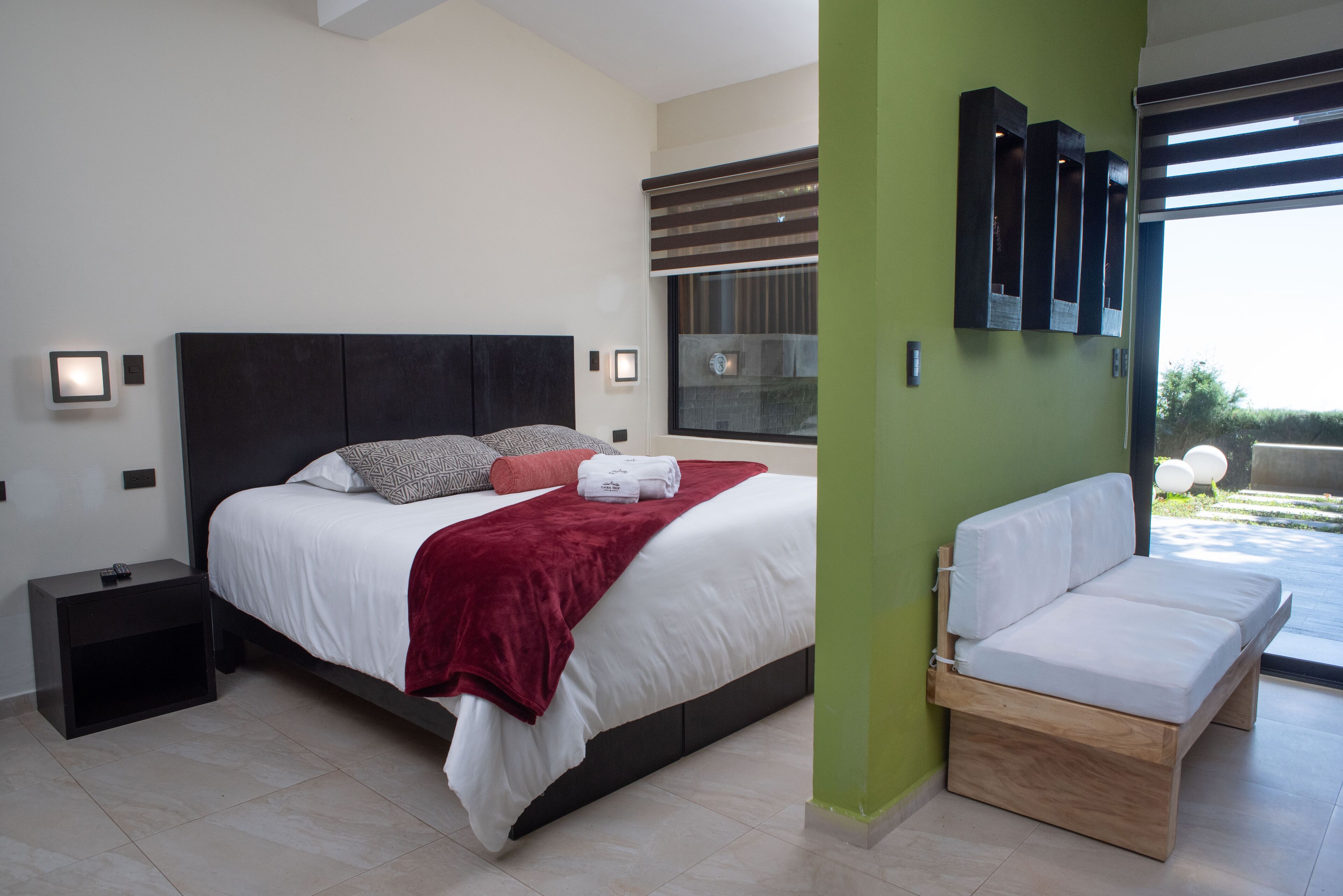 Een moderne slaapkamer met een groot bed, nachtkastjes en een ingebouwde bank.