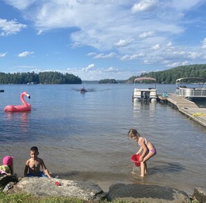 Un lac avec un quai, un flotteur en forme de flamant rose et un bateau.
