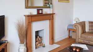 A living room with a fireplace, a television, a sofa, and a coffee table. - This apartment has wonderful views over Bowness to Lake Windermere. (Bowness on Windermere)