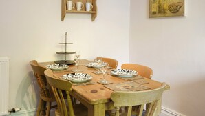 A wooden dining table set with plates, glasses, and a vase on a shelf labeled "SPICES". - This apartment has wonderful views over Bowness to Lake Windermere. (Bowness on Windermere)