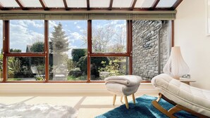 Une pièce dotée d’une grande verrière, d’un mur en pierre, d’un canapé blanc, d’un tapis bleu et d’un tapis blanc moelleux.