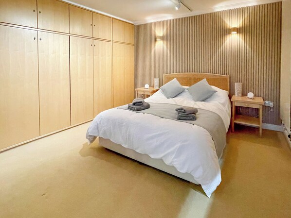 Un dormitorio con una cama grande, un armario de madera y mesitas de noche.
