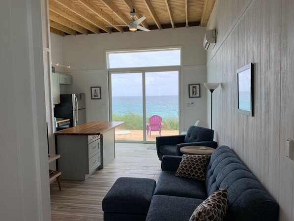 A modern interior with a kitchen, a sofa, and a view of the ocean.