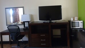 Una habitación de hotel con escritorio, televisión, microondas y una silla.