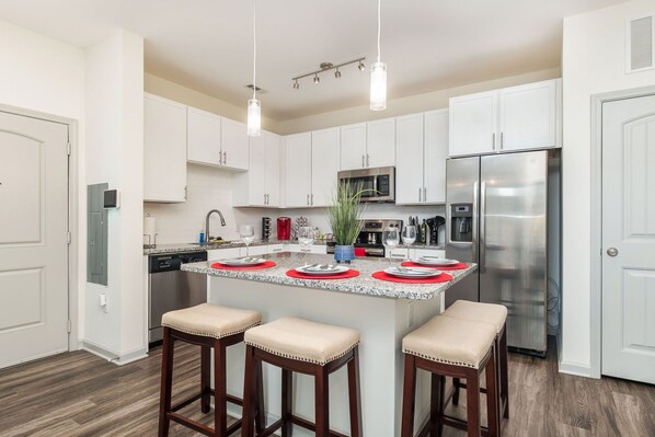 A modern kitchen with white cabinets, stainless steel appliances, and a central island with stools.