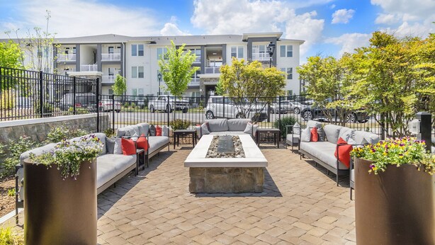 An outdoor patio area with seating, a fire pit, and a view of apartment buildings. - Luxury Apt | Work from here | King Bed | Fast WiFi |6mi to CLT✈️ (Charlotte)