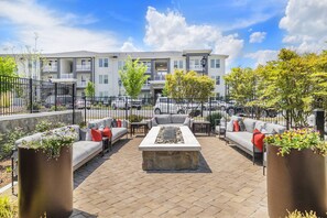 An outdoor patio area with seating, a fire pit, and a view of apartment buildings.