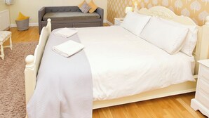 A bedroom with a large bed, a grey sofa, a small table, and a patterned wall. - Single storey cottage for 4/6 in Twynholm only 3 miles from Kirkcudbright. (Twynholm by Kirkcudbright)