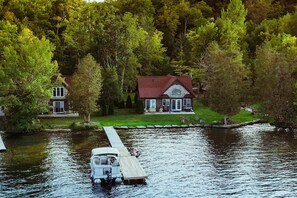A house with a dock extending into a lake, surrounded by trees.