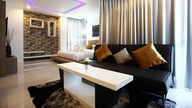 A modern living room with a sofa, a coffee table, and a stone wall. - Buasri Boutique Patong (Patong)