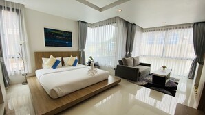 A modern hotel room with a large bed, a sofa, a small table, and a painting on the wall. - Buasri Boutique Patong (Patong)